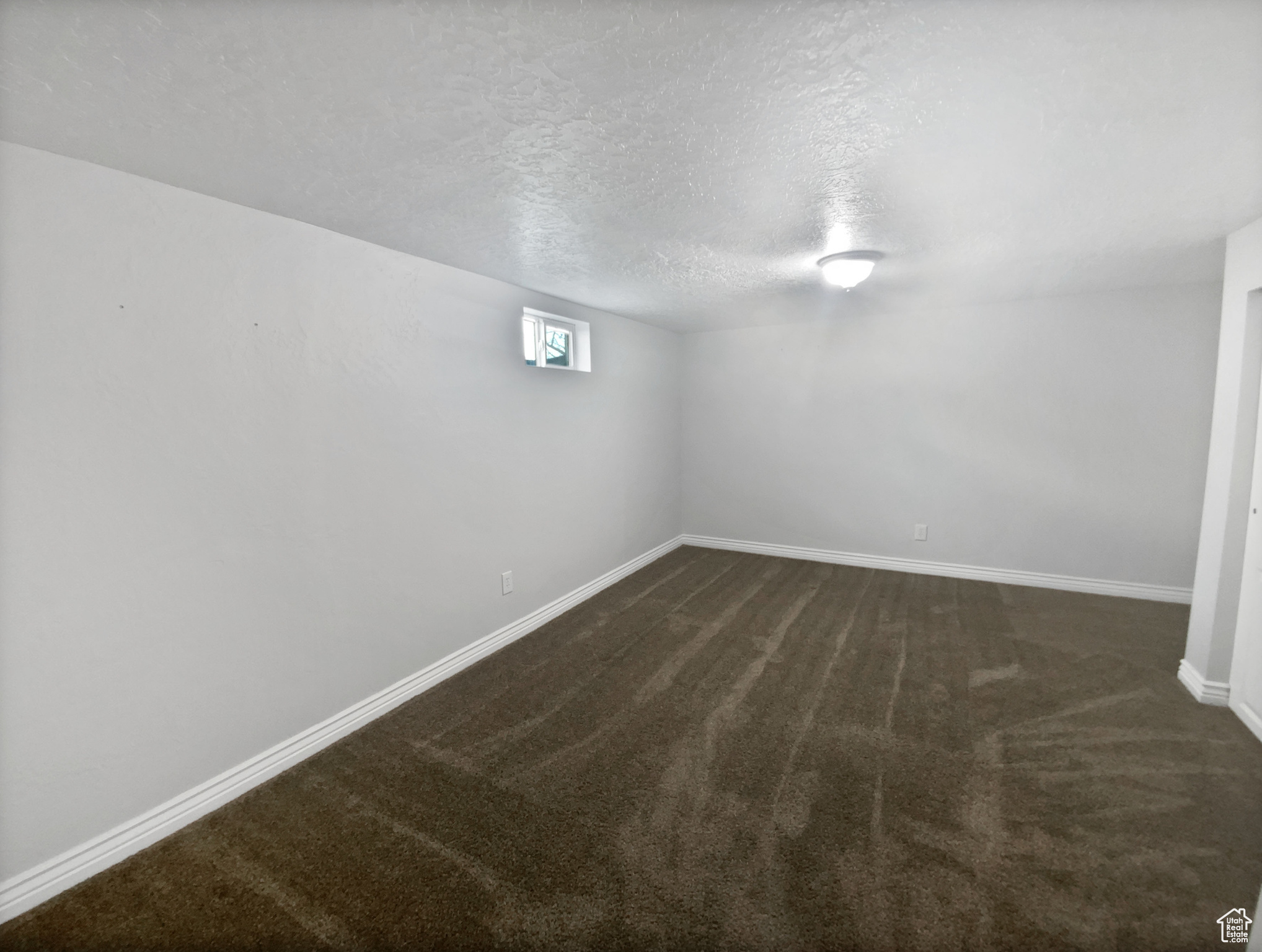 Basement featuring a textured ceiling and dark carpet