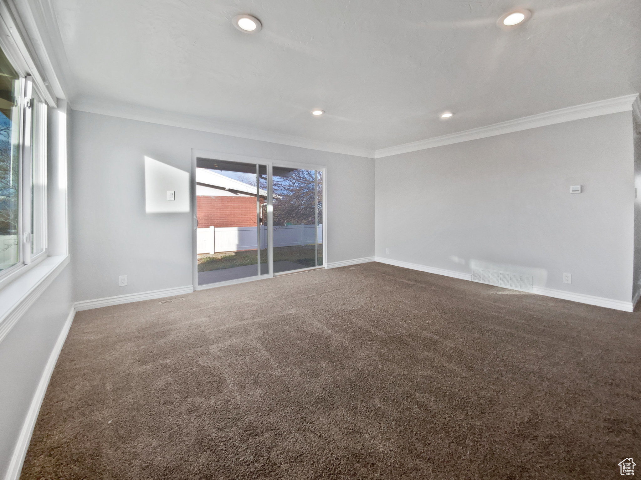 Carpeted empty room featuring ornamental molding