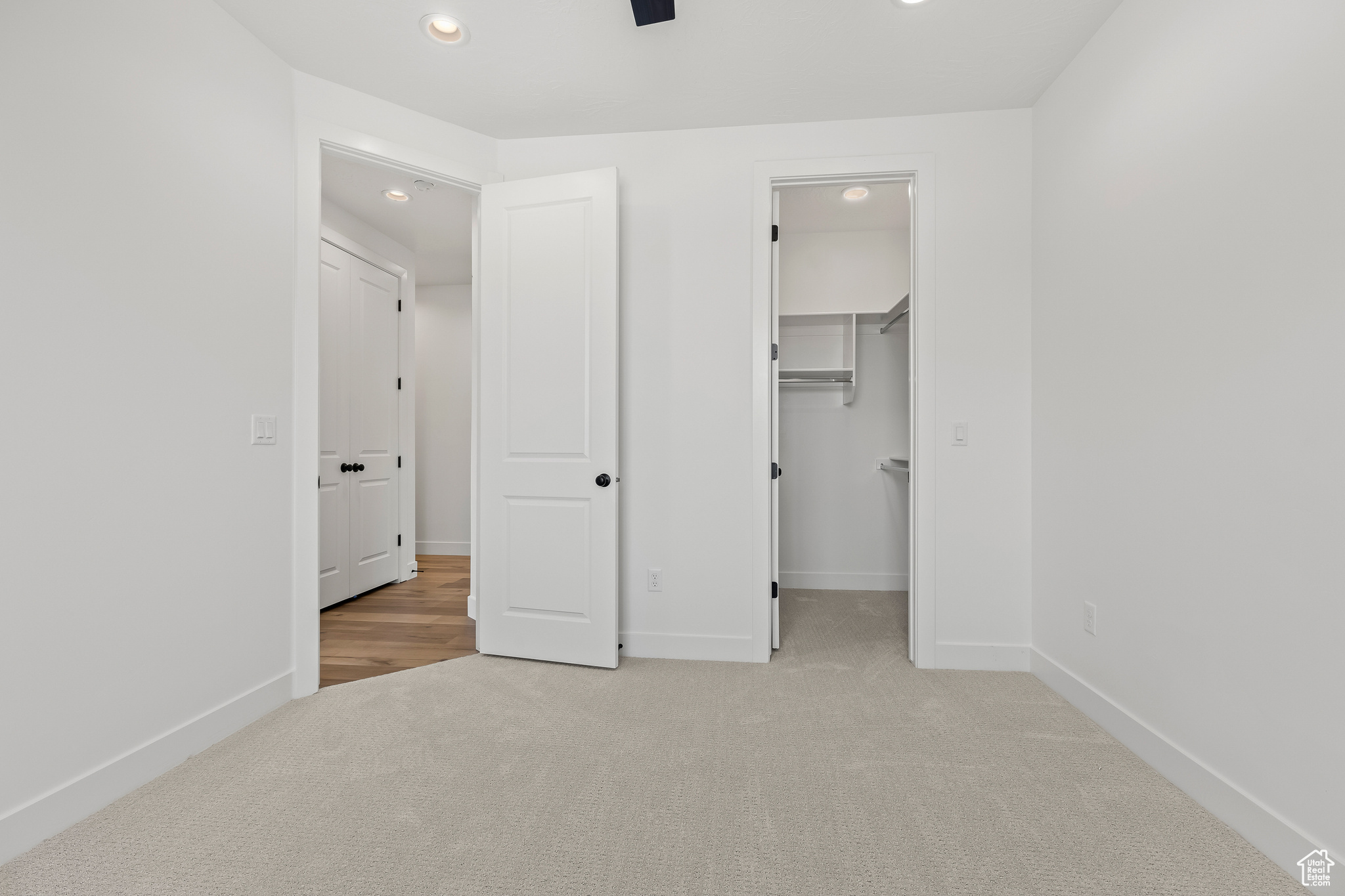 Unfurnished bedroom with light colored carpet, a spacious closet, and a closet