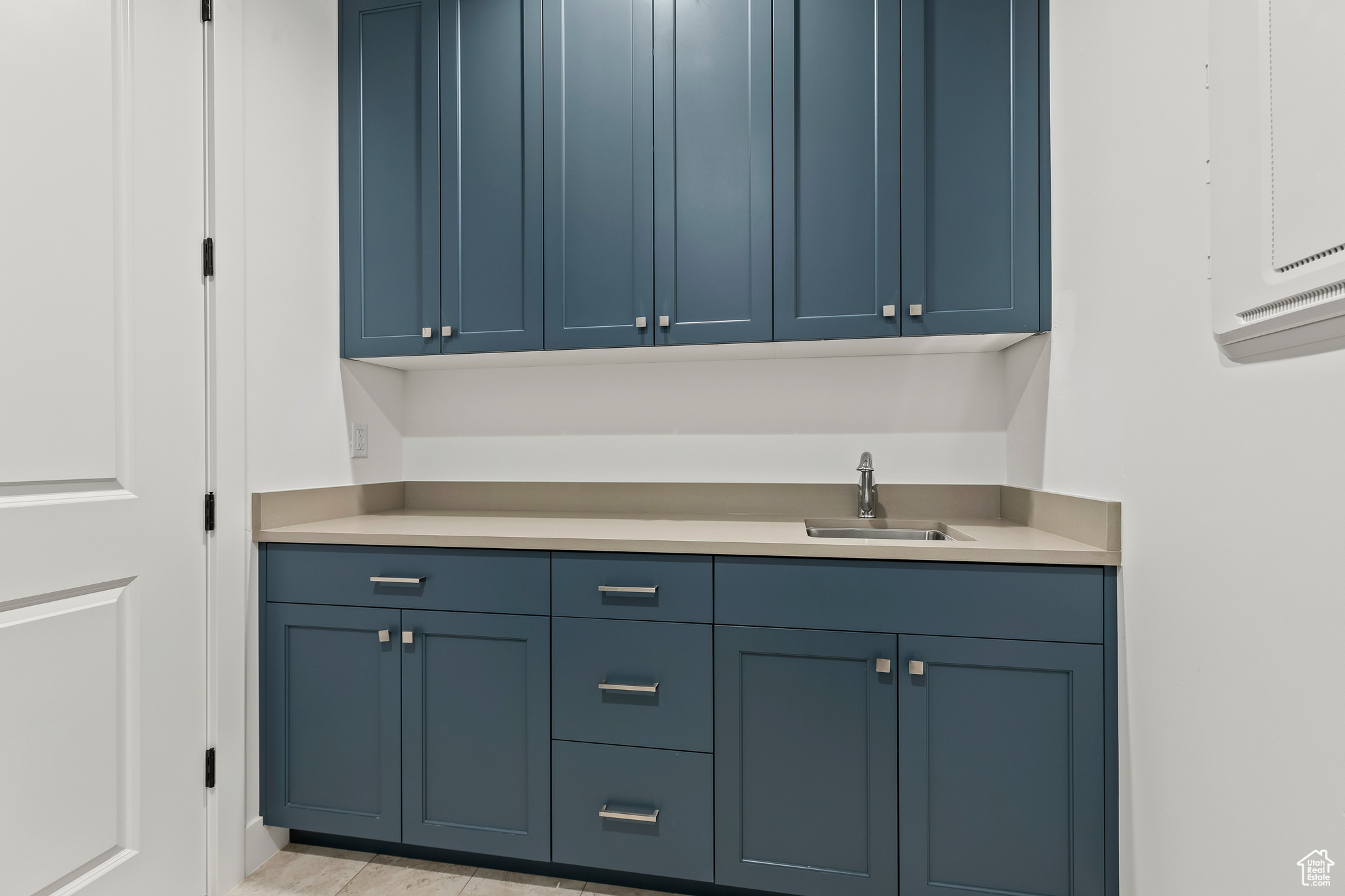 Interior space featuring blue cabinetry, light tile patterned floors, sink, and electric panel