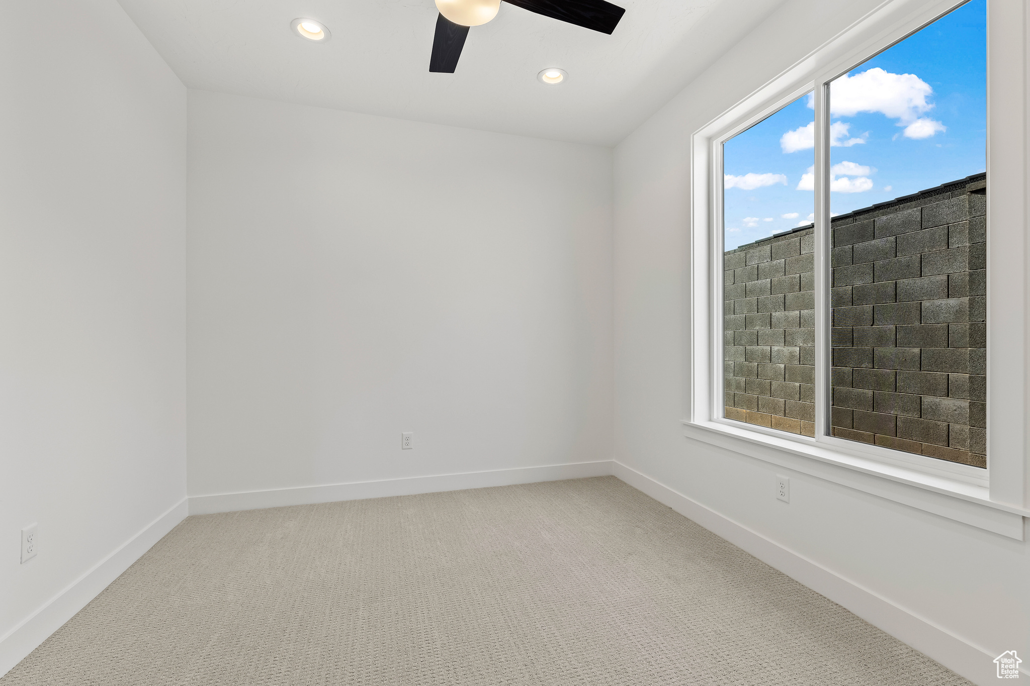 Unfurnished room with ceiling fan, carpet floors, and a wealth of natural light