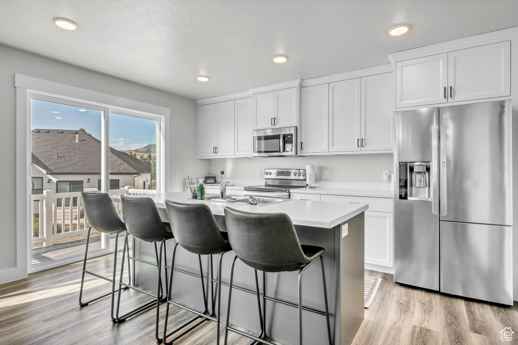 Kitchen featuring white cabinetry, a center island with sink, and stainless steel appliances