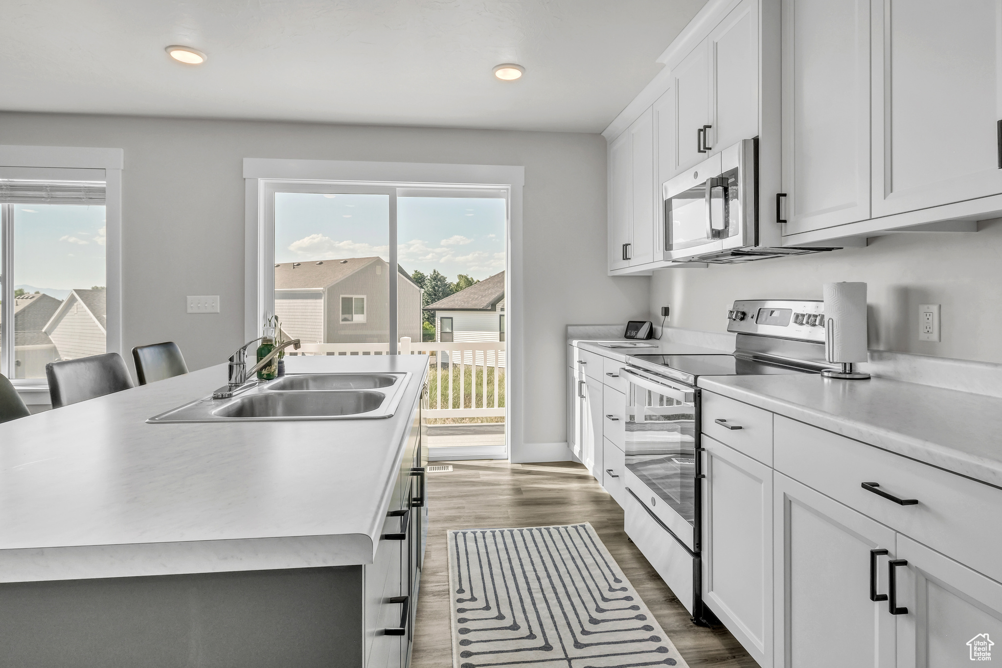 Kitchen featuring stainless steel appliances, sink, a center island with sink, white cabinets, and a breakfast bar area