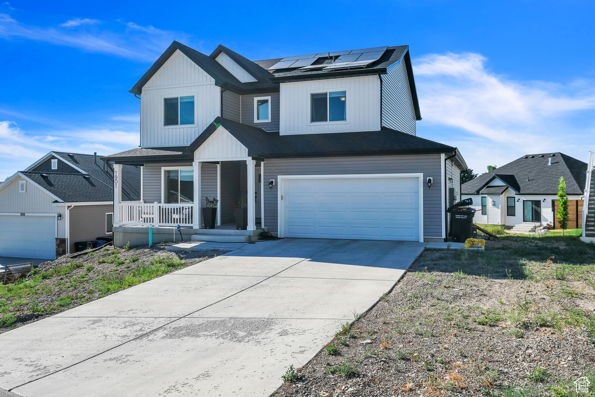 View of front of property featuring a porch, solar panels, and a garage