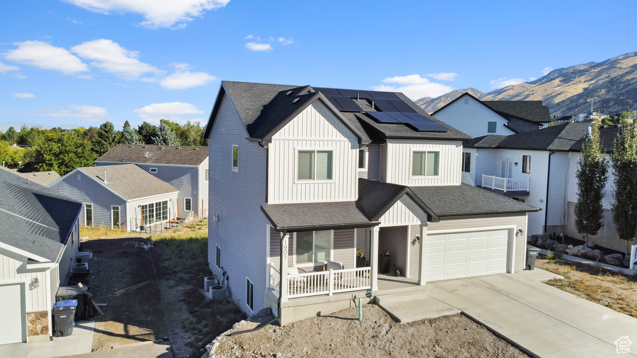 View of front facade with solar panels, a mountain view, cooling unit, a garage, and a porch