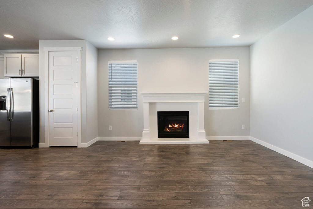 Unfurnished living room featuring a textured ceiling and dark hardwood / wood-style floors