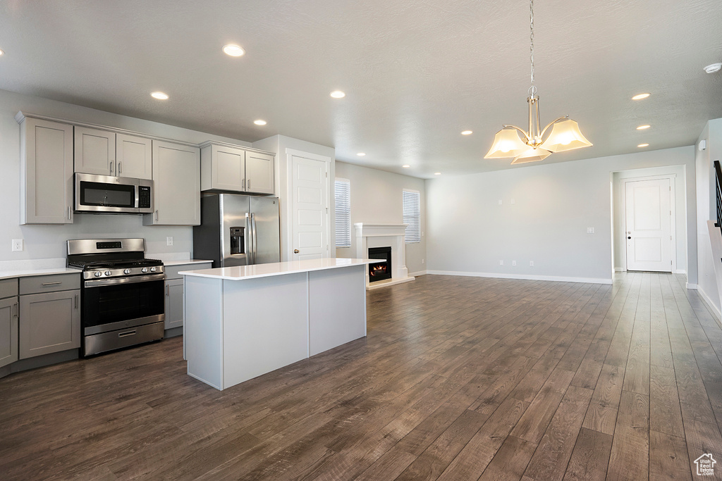 Kitchen featuring appliances with stainless steel finishes, gray cabinetry, decorative light fixtures, dark hardwood / wood-style floors, and a kitchen island