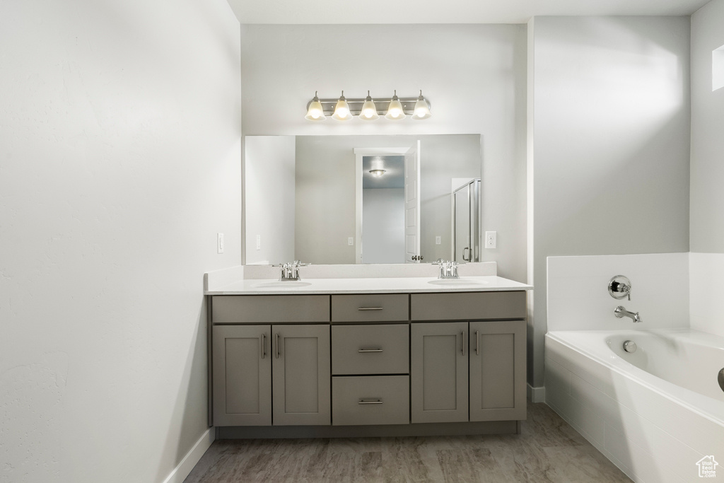 Bathroom with a washtub, wood-type flooring, and vanity