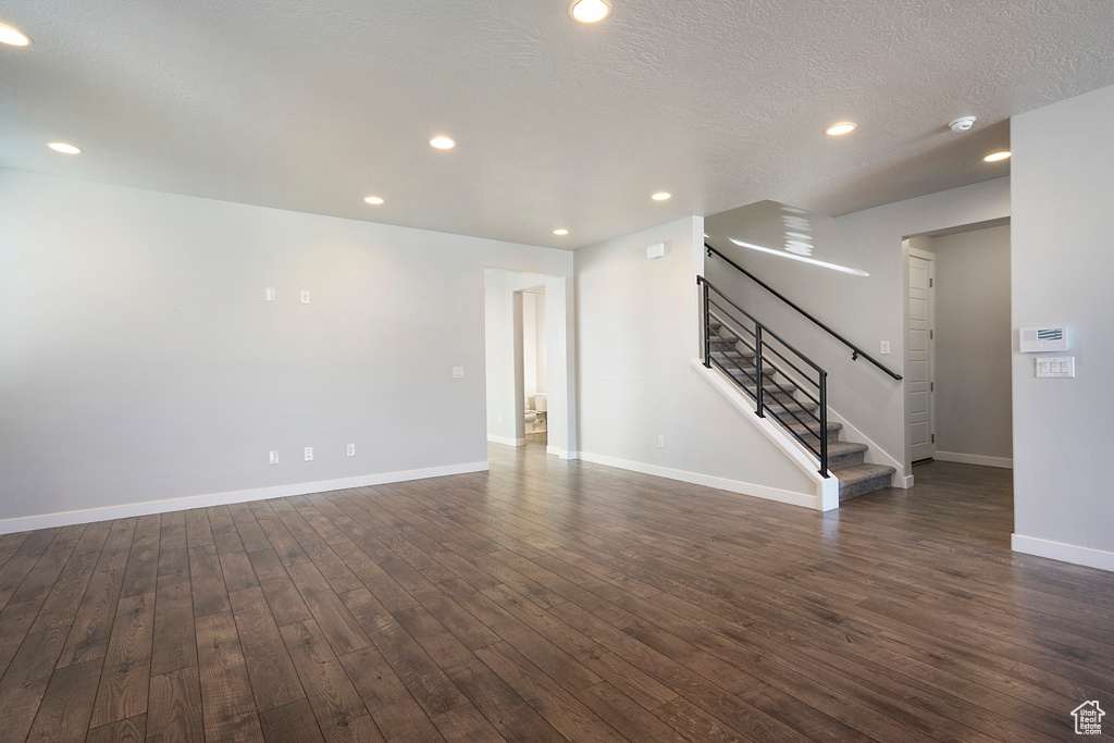 Empty room featuring a textured ceiling and dark hardwood / wood-style floors