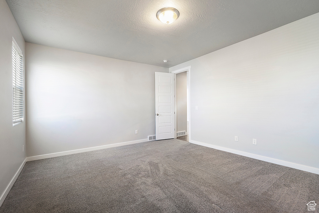 Carpeted spare room with a textured ceiling