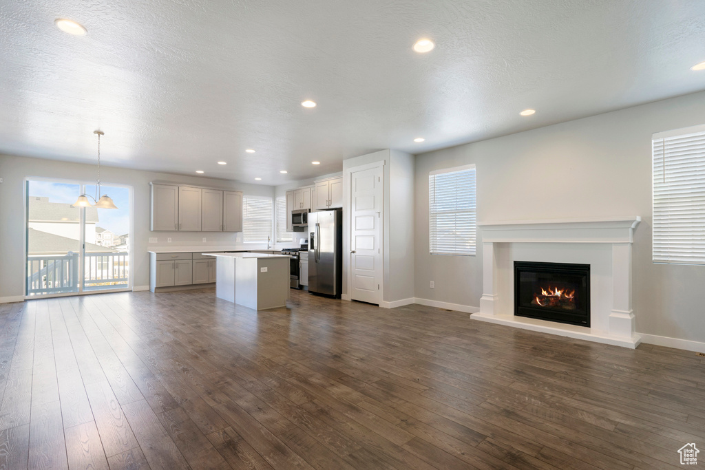 Unfurnished living room with sink, dark hardwood / wood-style flooring, a textured ceiling, and an inviting chandelier