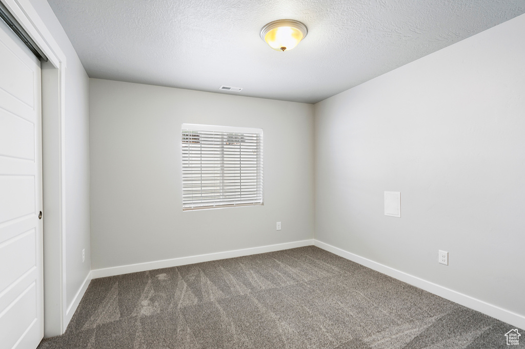 Carpeted empty room featuring a textured ceiling