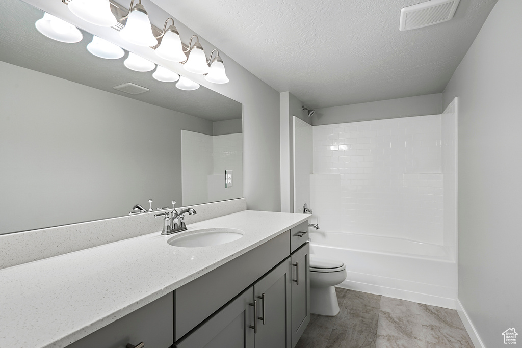 Full bathroom with a textured ceiling, vanity,  shower combination, and toilet