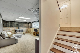 Interior space with carpet flooring, a wood stove, and a paneled ceiling