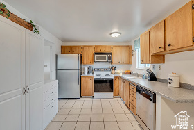 Kitchen featuring light tile patterned flooring and appliances with stainless steel finishes