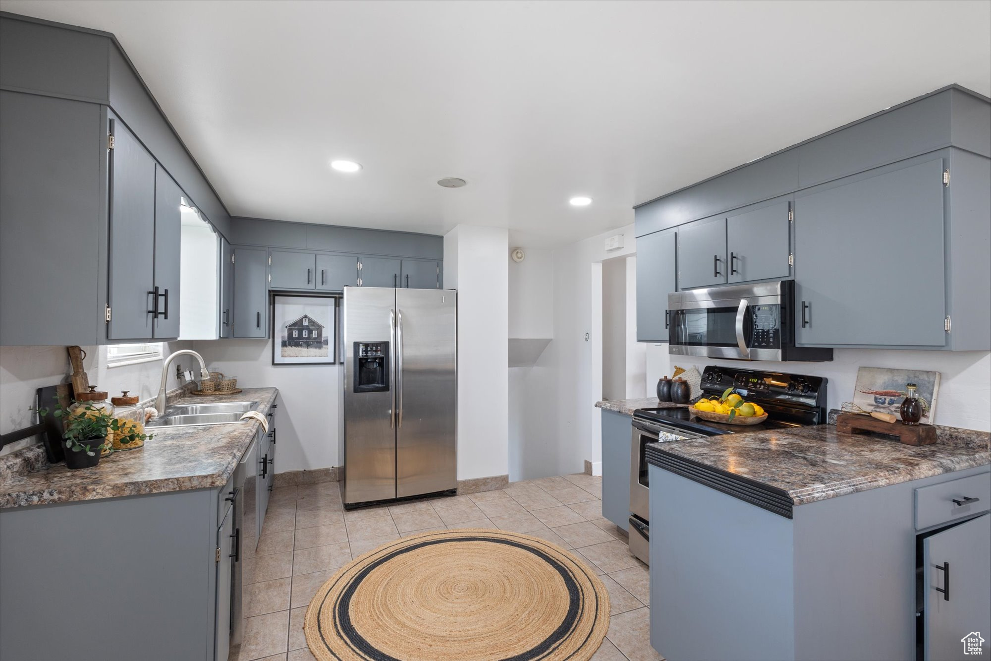 Kitchen featuring gray cabinets, sink, light tile patterned flooring, and appliances with stainless steel finishes