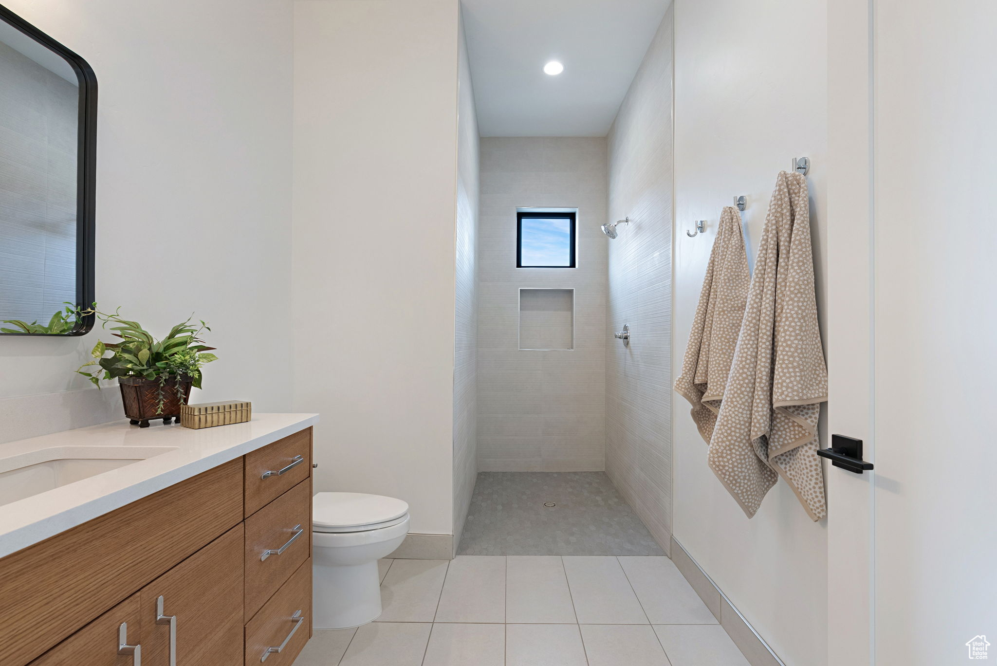 En Suite Bathroom featuring tiled shower, tile patterned flooring, vanity, and toilet