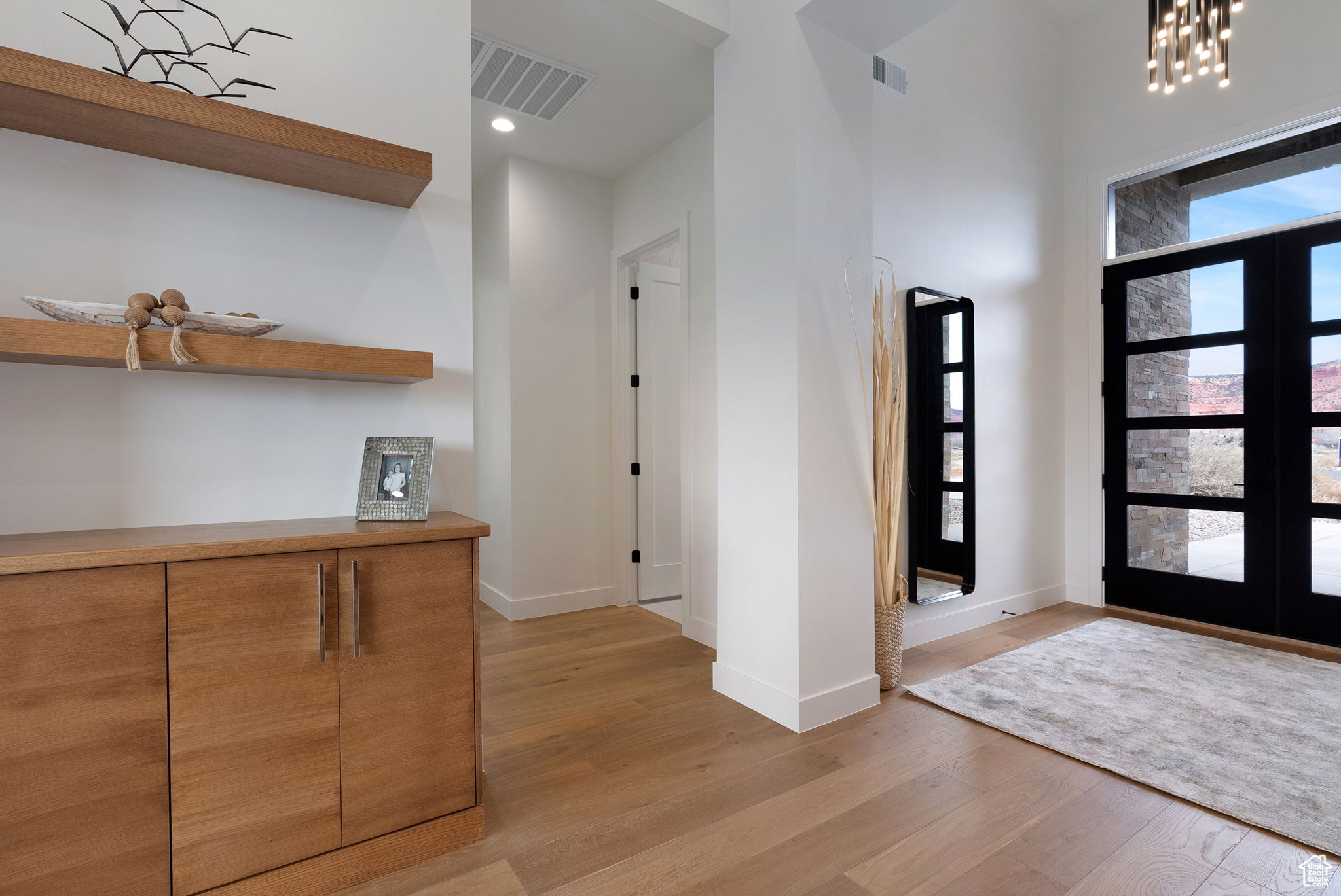 Foyer entrance featuring an inviting chandelier, light hardwood / wood-style flooring, and french doors