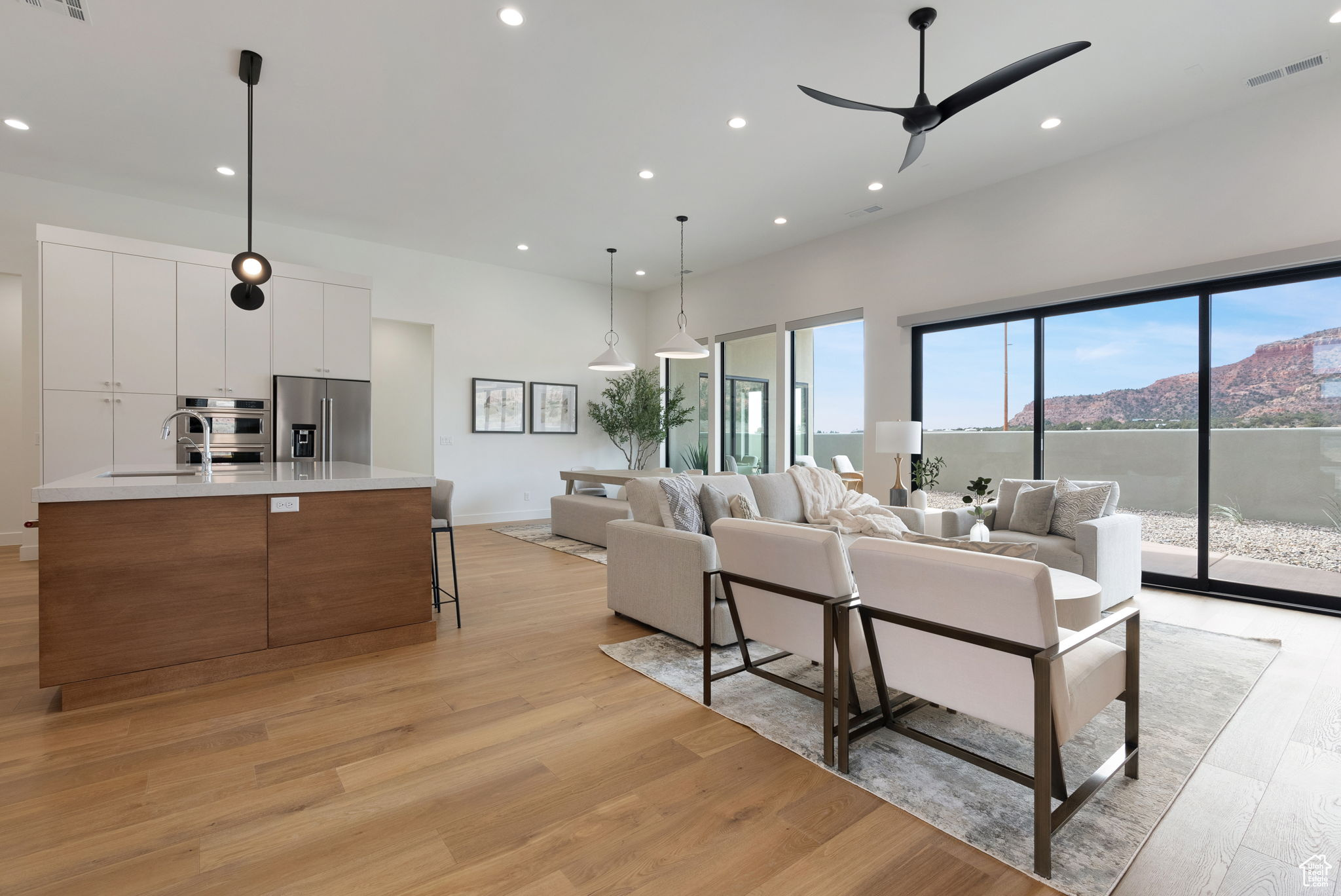 Living room with a mountain view, light hardwood / wood-style flooring, ceiling fan, and sink