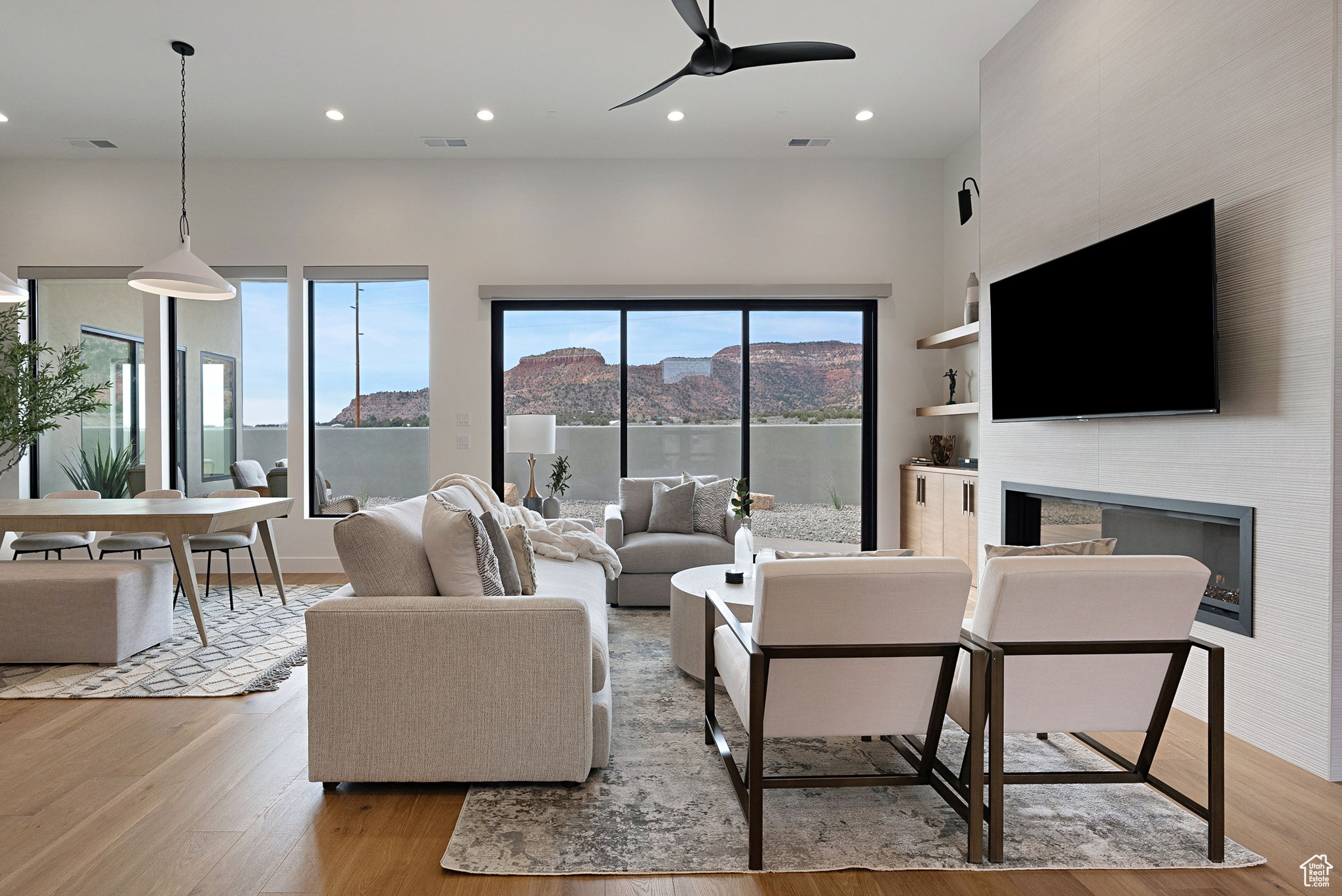 Living room featuring built in shelves, a large fireplace, light hardwood / wood-style floors, and ceiling fan