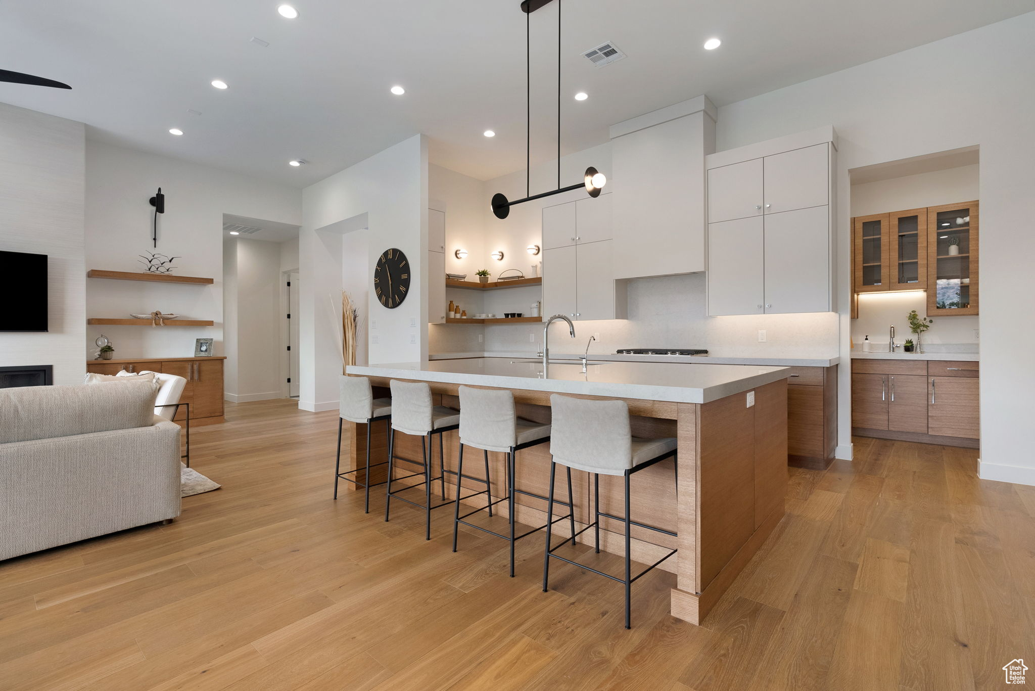 Kitchen with white cabinetry, a breakfast bar area, a fireplace, a center island with sink, and light wood-type flooring