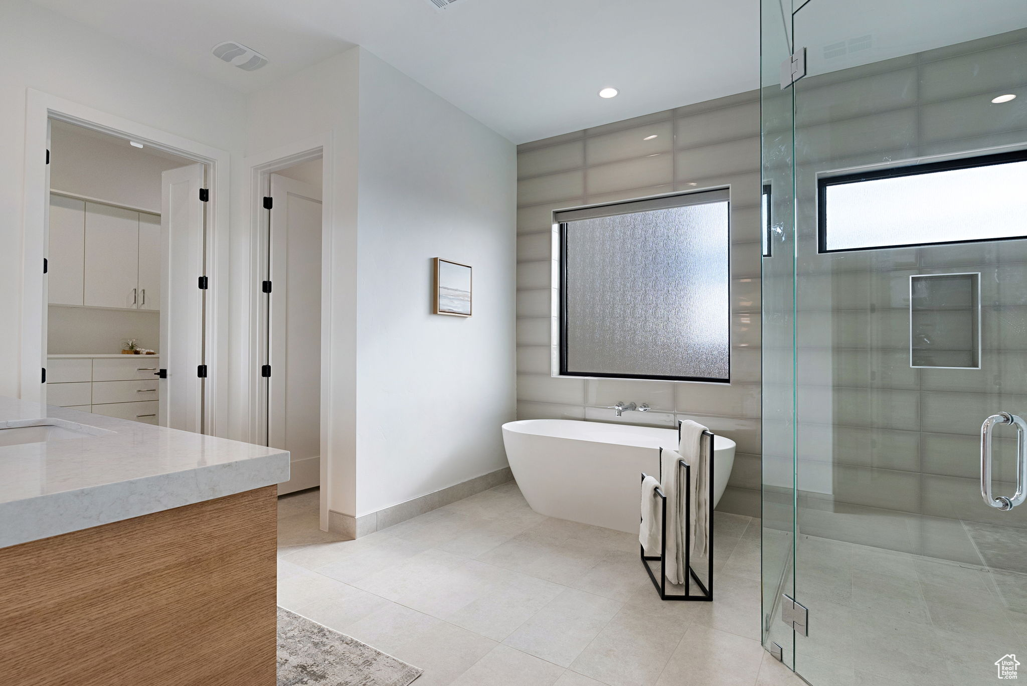 Bathroom featuring plus walk in shower, tile patterned flooring, and vanity