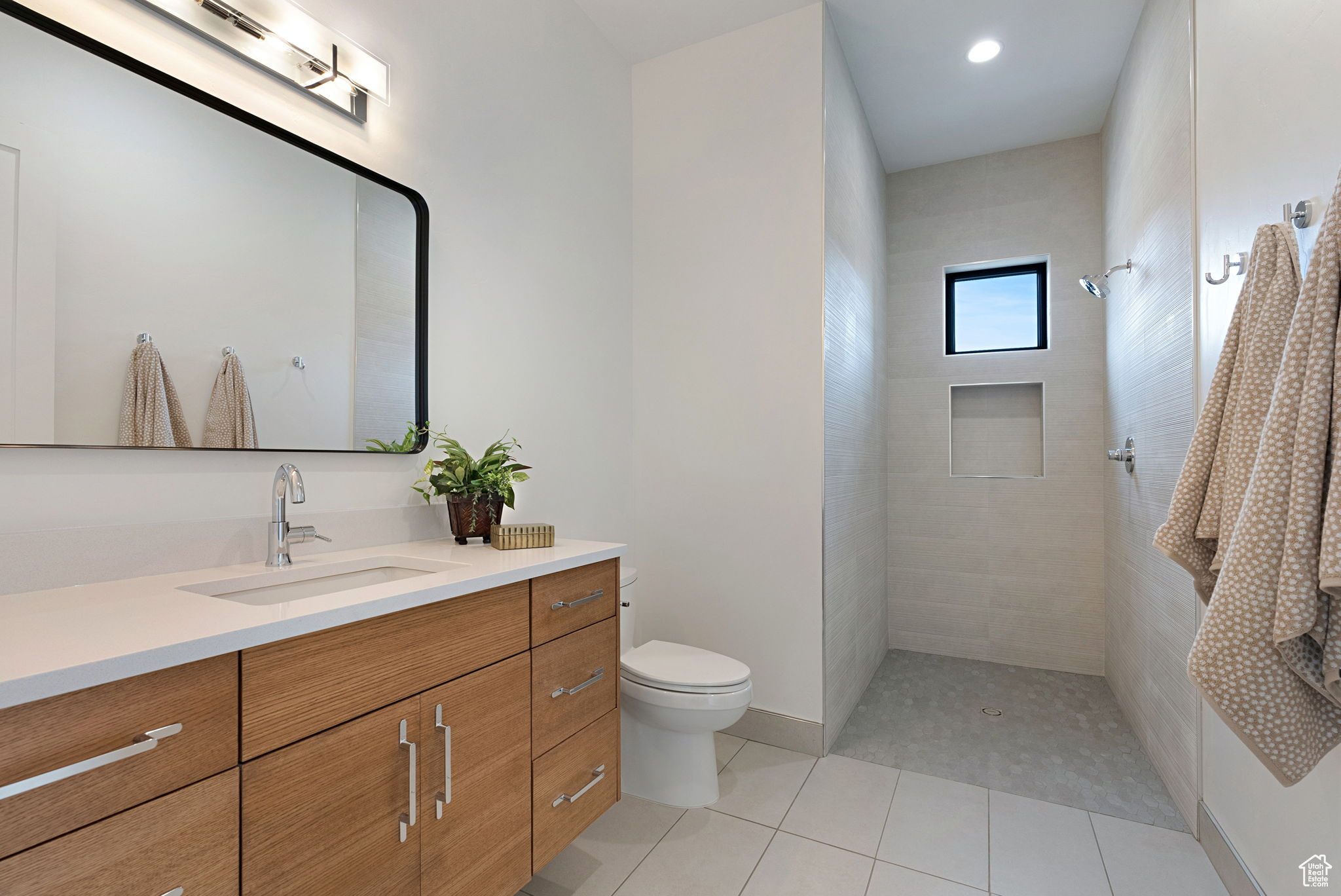 Bathroom featuring tile patterned floors, vanity, a tile shower, and toilet