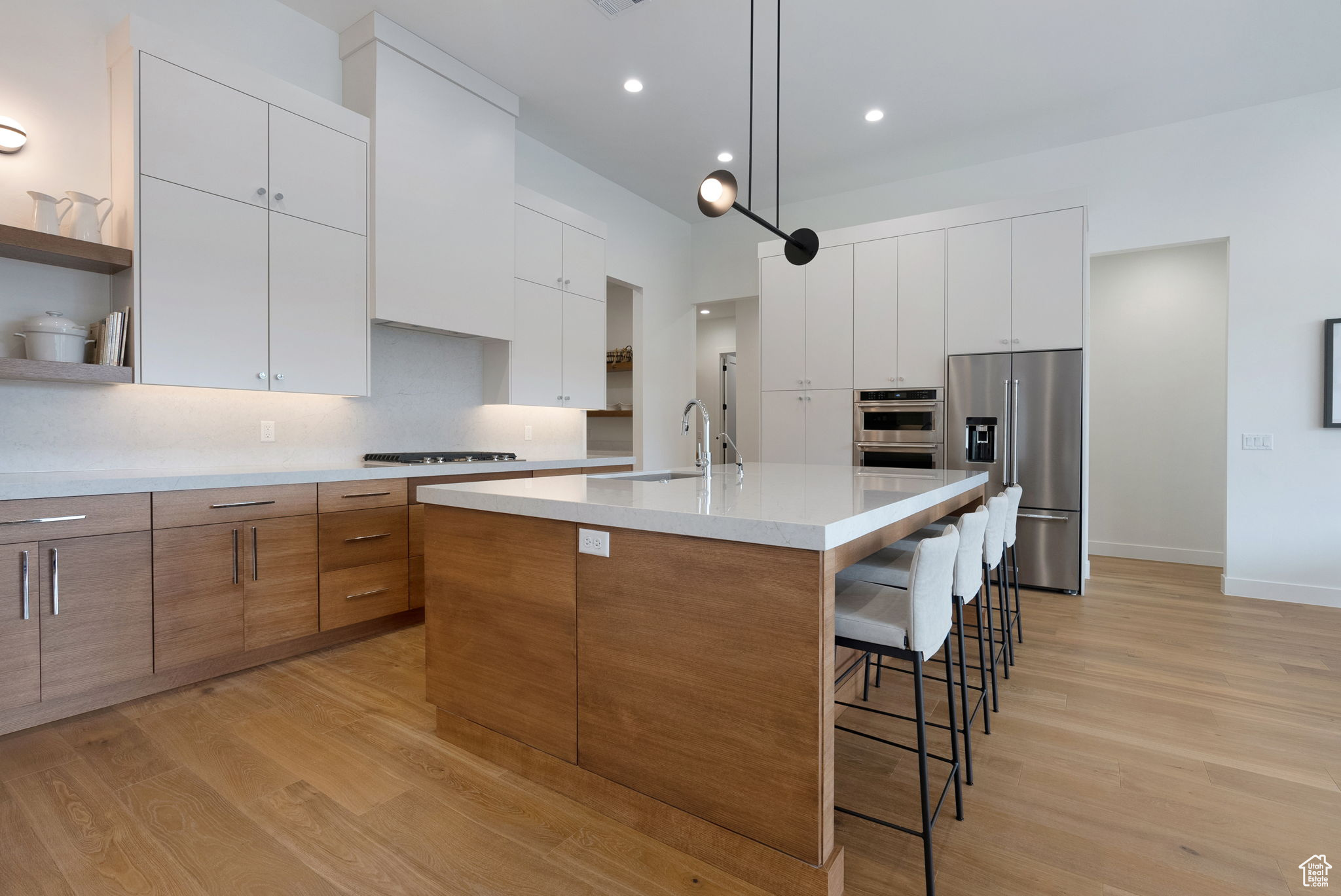 Kitchen featuring appliances with stainless steel finishes, sink, white cabinetry, and an island with sink