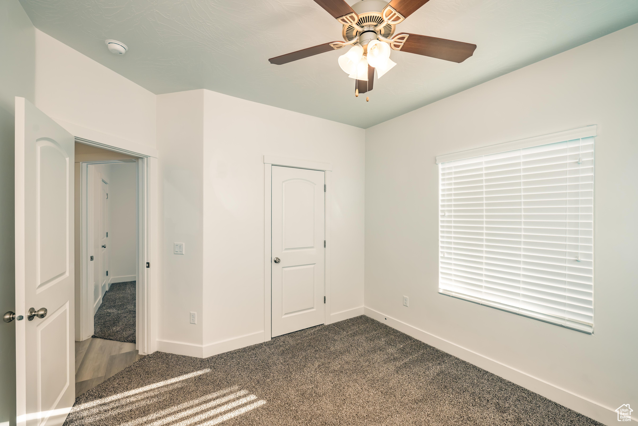 Unfurnished bedroom featuring carpet flooring, ceiling fan, and a closet