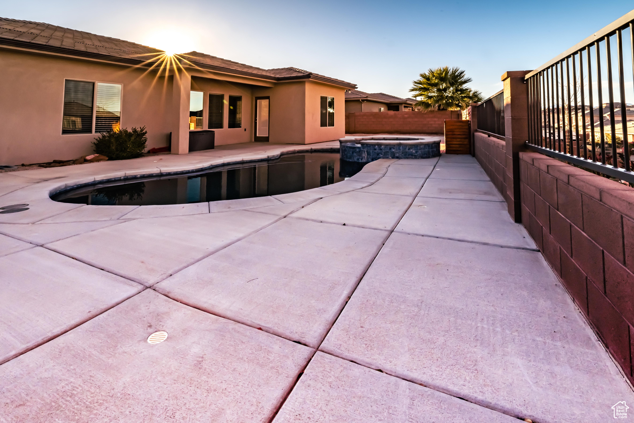 Pool at dusk featuring an in ground hot tub and a patio