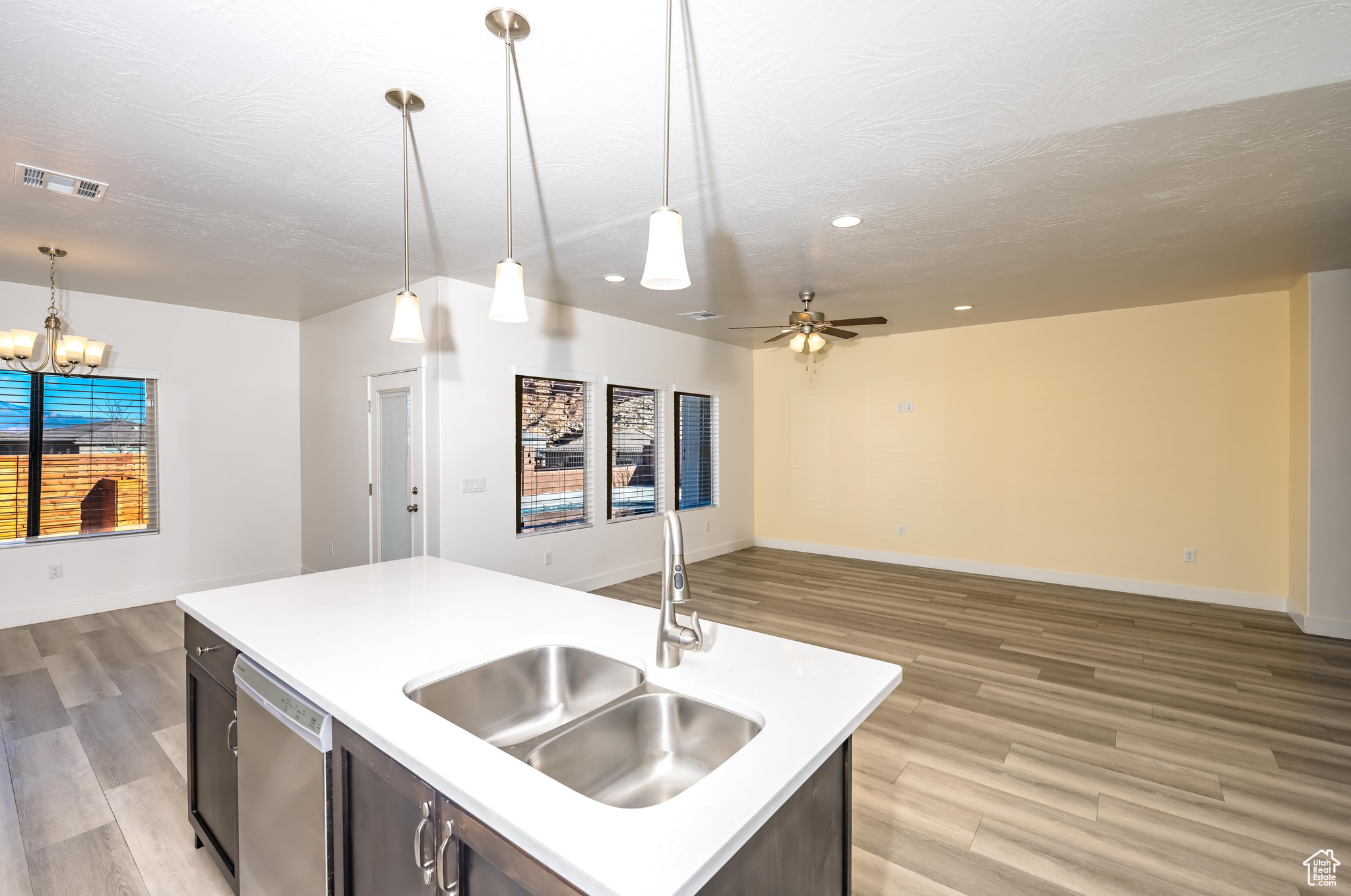 Kitchen with sink, pendant lighting, a center island with sink, light hardwood / wood-style flooring, and dishwasher