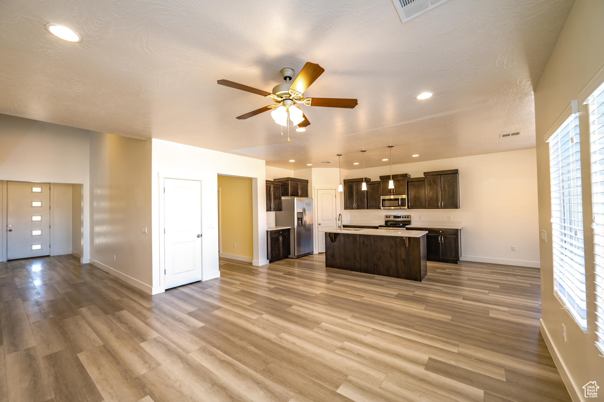 Kitchen with appliances with stainless steel finishes, a wealth of natural light, pendant lighting, and an island with sink