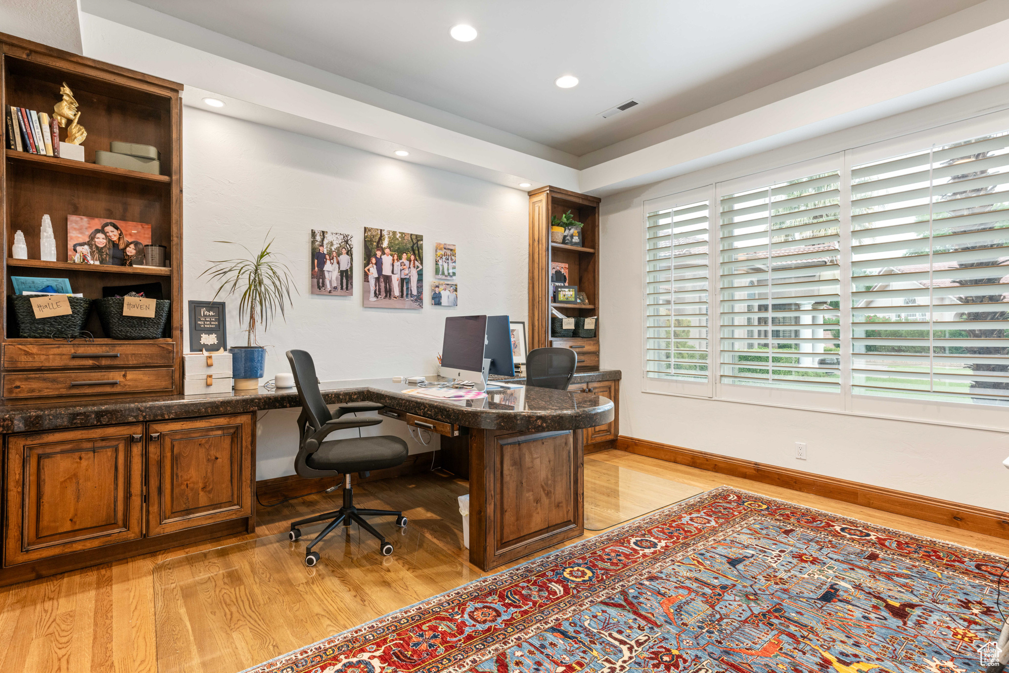 Home office with built in desk and light hardwood / wood-style flooring