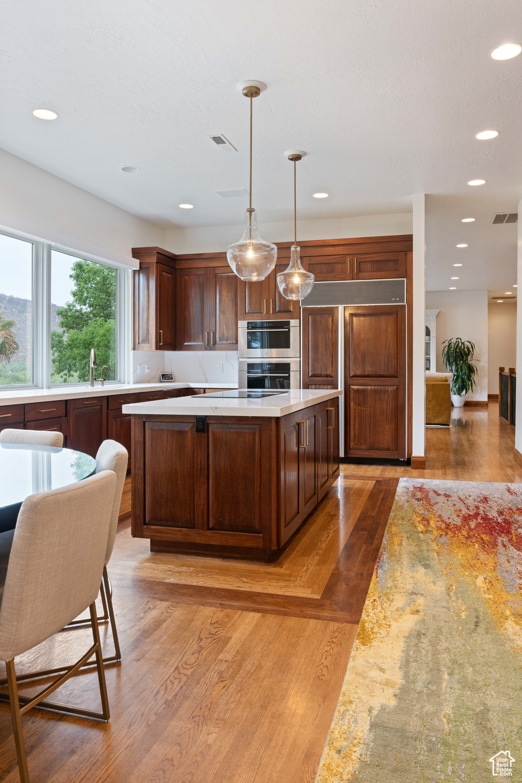 Kitchen featuring light wood-type flooring, dark brown cabinets, sink, decorative light fixtures, and a center island