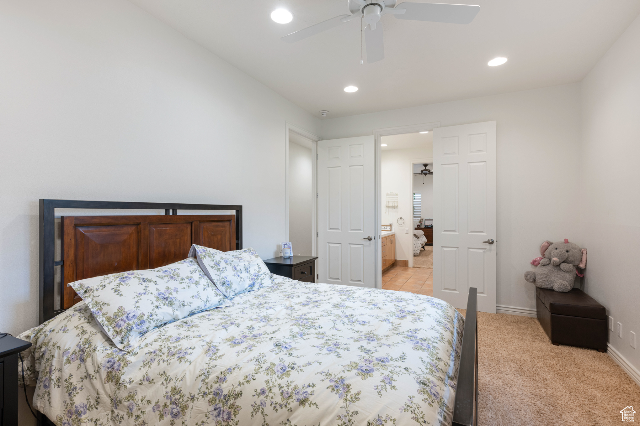 Bedroom with ceiling fan, ensuite bathroom, and light carpet