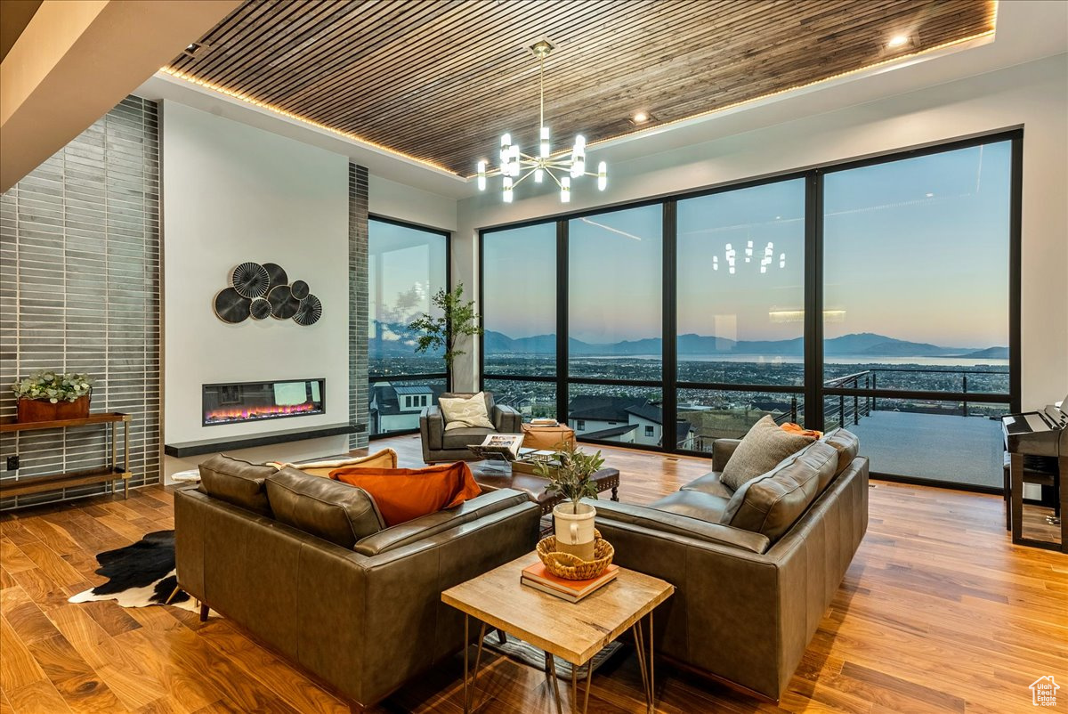 Living room featuring a chandelier, light hardwood / wood-style flooring, wooden ceiling, and plenty of natural light