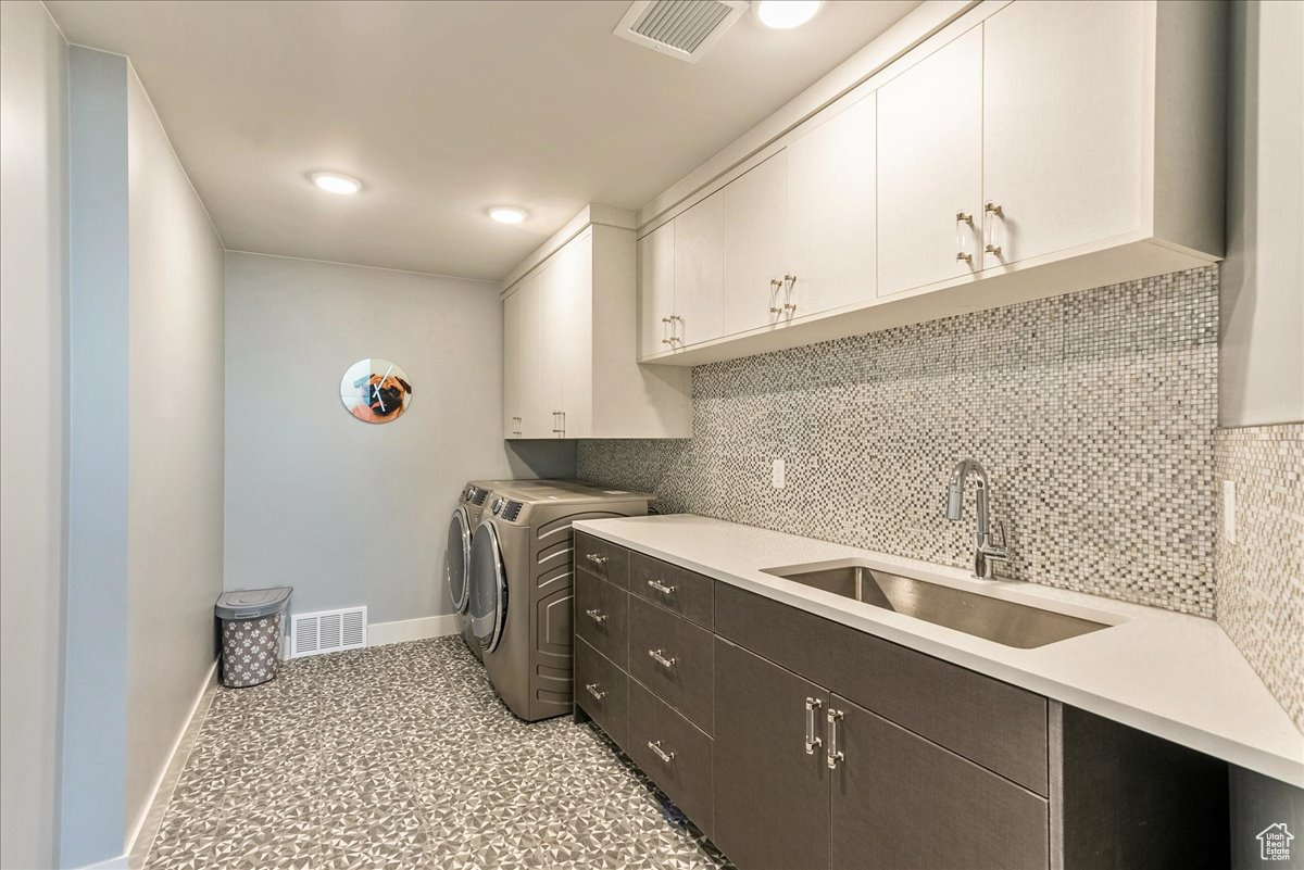 Laundry room featuring washer and clothes dryer, sink, and cabinets