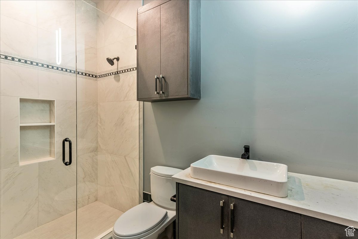 Bathroom with vanity, toilet, and a shower with shower door