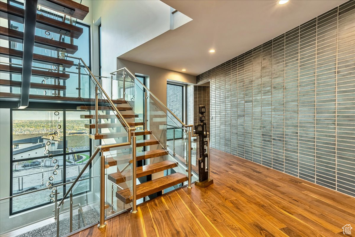 Staircase with tile walls and hardwood / wood-style flooring