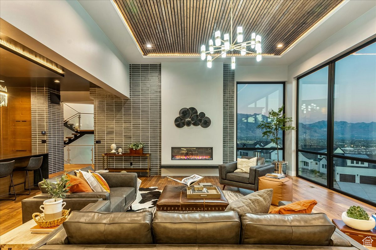 Living room featuring a tray ceiling, wooden ceiling, wood-type flooring, and an inviting chandelier