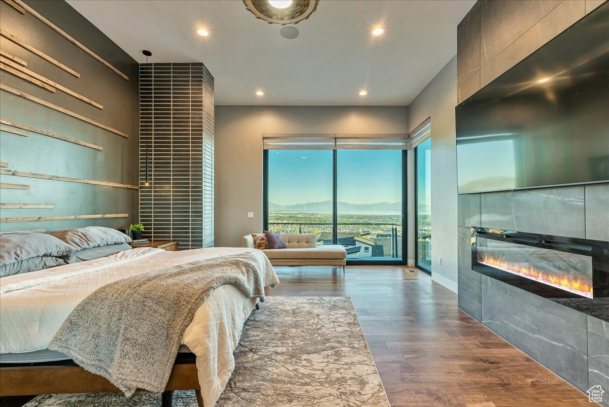 Bedroom featuring access to outside, a tiled fireplace, and hardwood / wood-style flooring