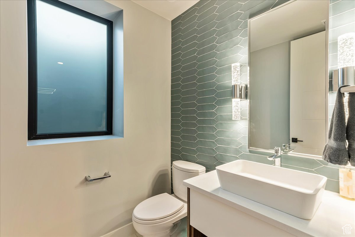 Bathroom featuring vanity, toilet, and tile walls