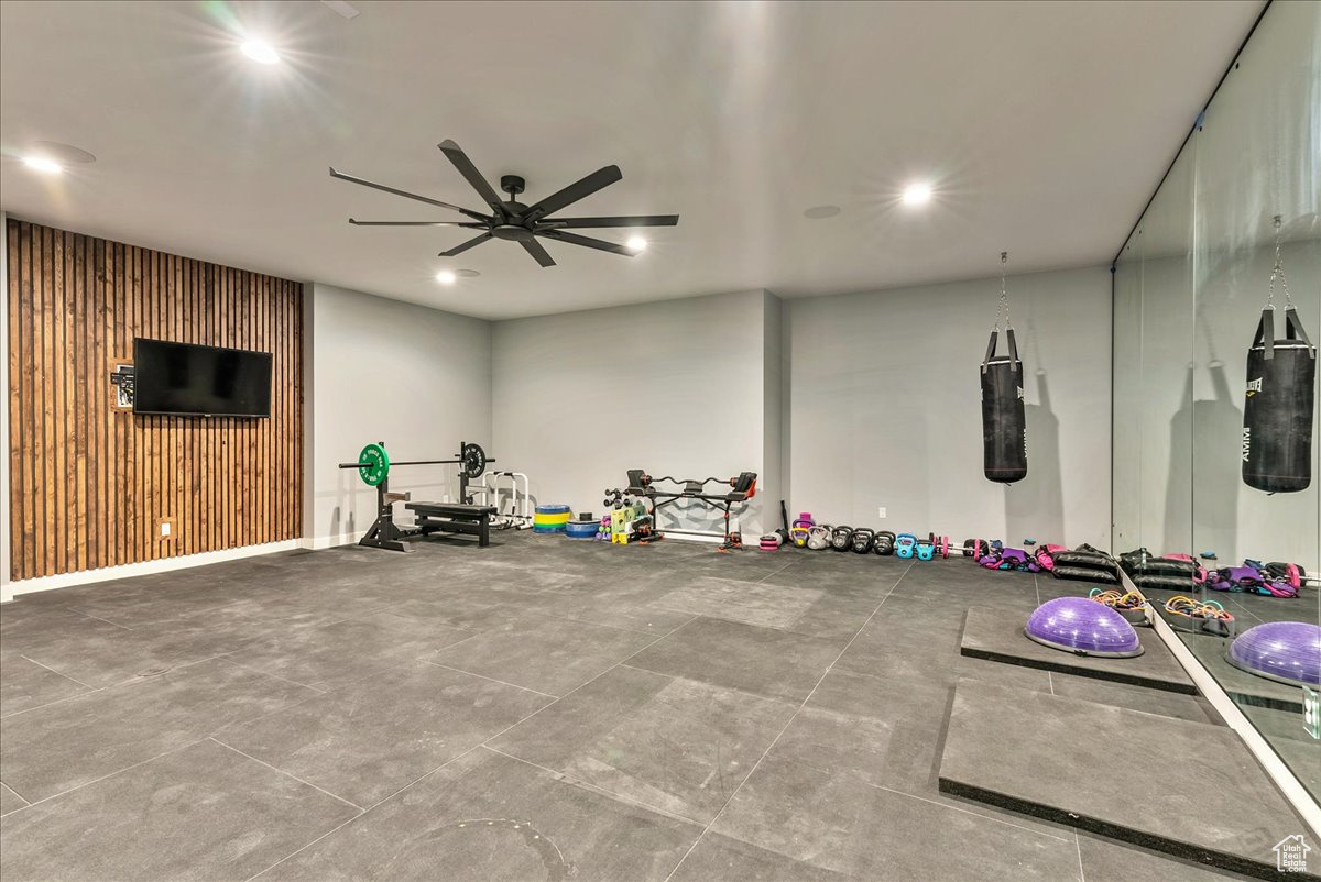 Workout room featuring ceiling fan and wood walls