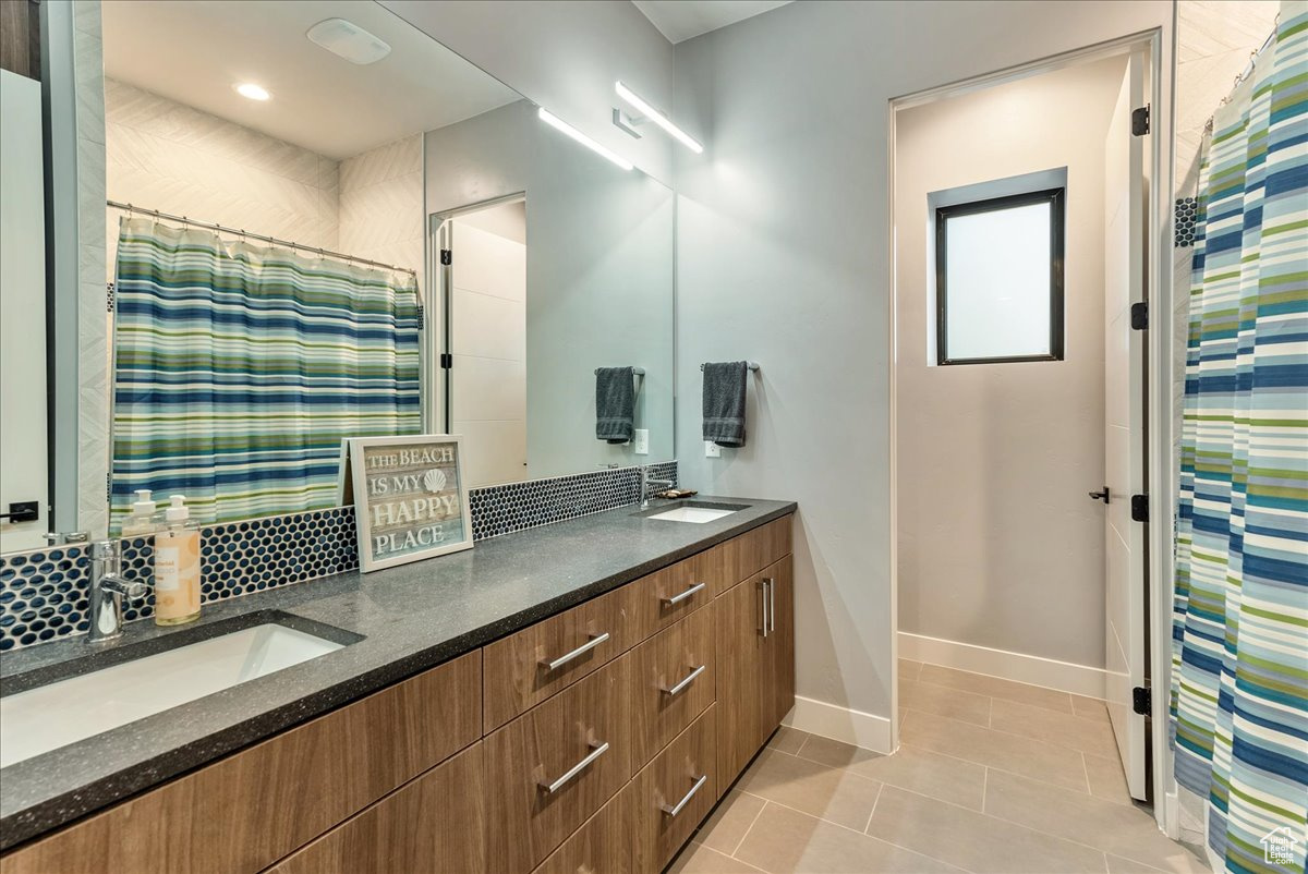 Bathroom with tile patterned floors, vanity, and curtained shower