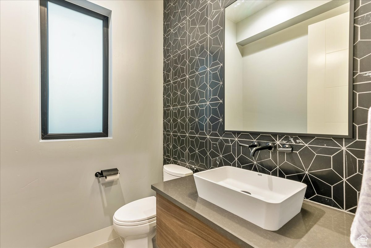 Bathroom with vanity, toilet, and tile walls