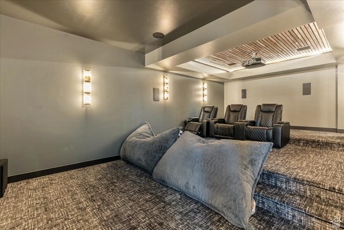 Home theater featuring dark colored carpet and a raised ceiling