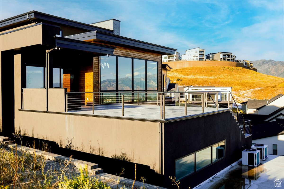 View of property exterior featuring central AC, a mountain view, and a balcony