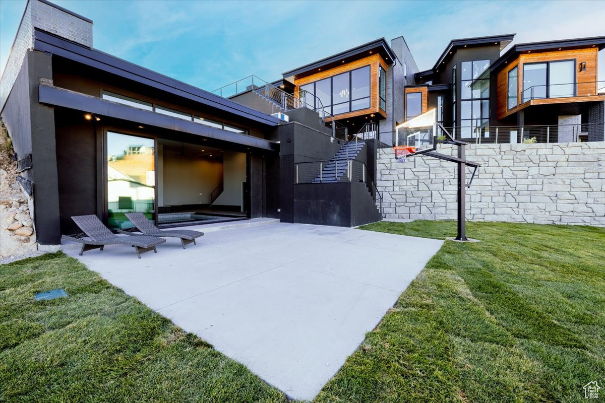 Rear view of property with a yard, basketball court, and a patio