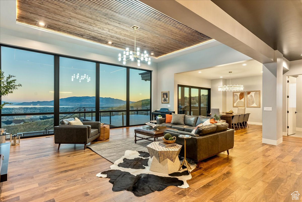 Living room featuring a mountain view, a raised ceiling, light wood-type flooring, a notable chandelier, and wood ceiling