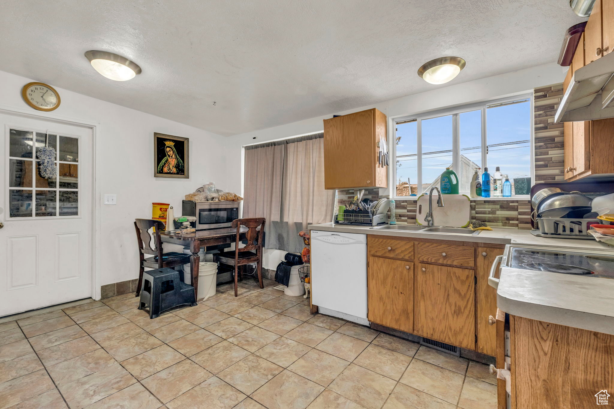 Kitchen with backsplash, white dishwasher, sink, a textured ceiling, and light tile patterned flooring